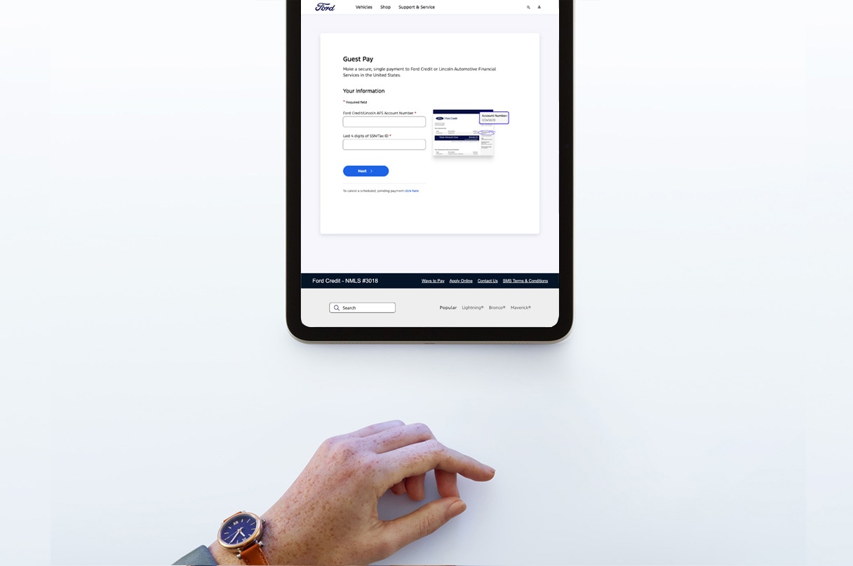 A women’s hand reaching towards a tablet that shows Ford Credit’s website.